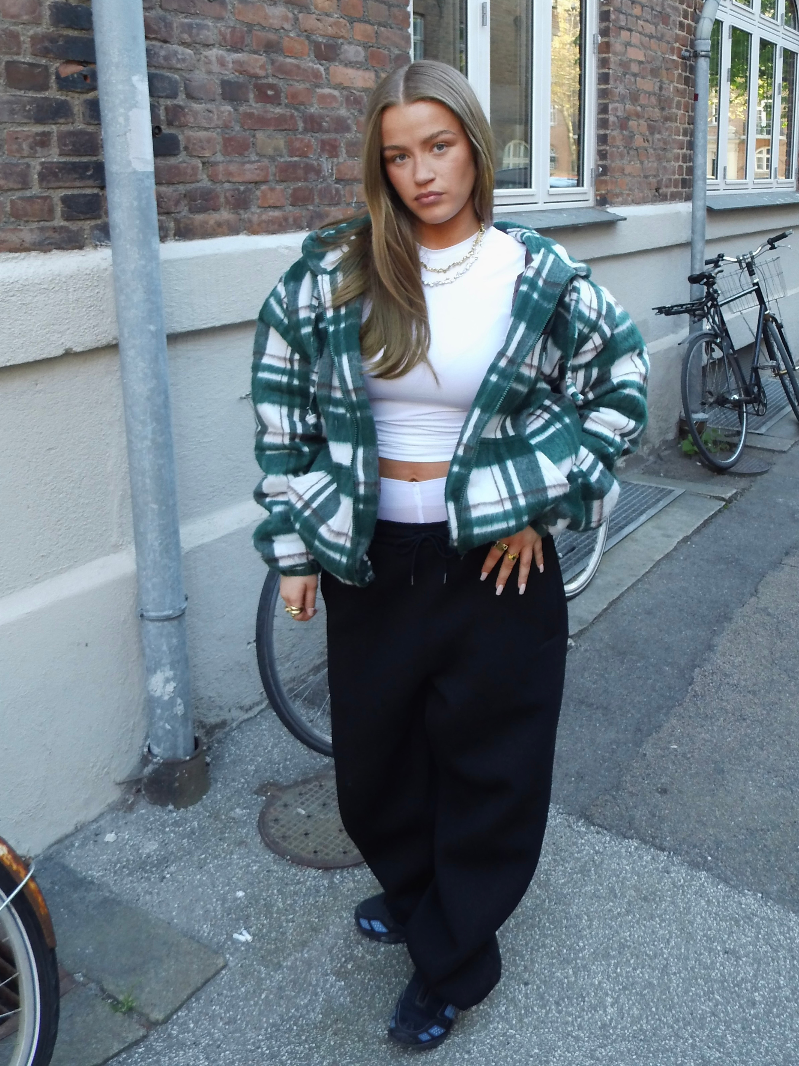 Kvinna i grönrutig jacka och svarta byxor, street style modebild
